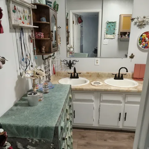 Bathroom featuring a dual vanity with white cabinetry, a light-toned countertop, and undermount sinks with black fixtures