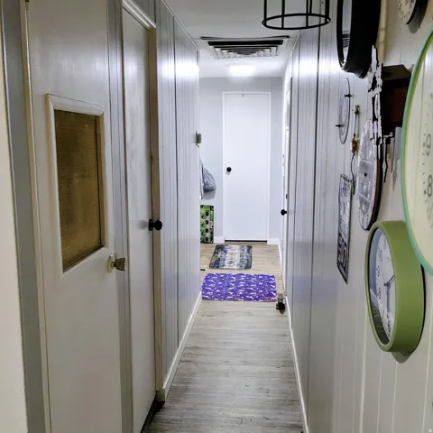 Hallway featuring wood-finish flooring, vertical paneling, recessed lighting, and solid interior doors