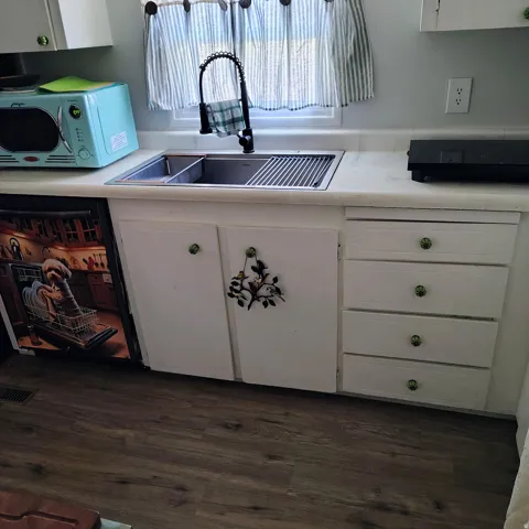 Kitchen sink area featuring a stainless steel double basin sink with an integrated drying rack and a matte black gooseneck faucet
