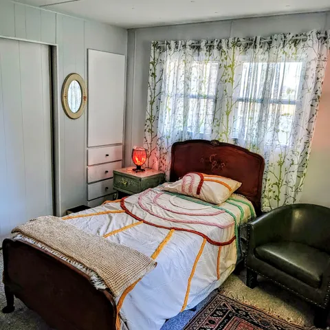 Room featuring a window with sheer patterned curtains, light-colored wall paneling, and a built-in closet with sliding doors
