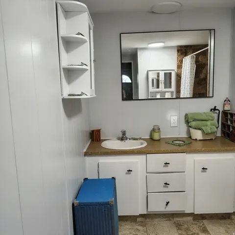 Vanity with an integrated sink, laminate countertop, and white cabinetry featuring black hardware