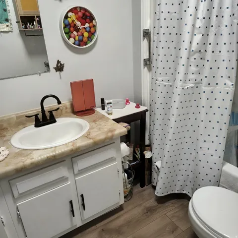 Bathroom featuring a vanity with a drop-in sink, dark bronze faucet, and light-toned countertop