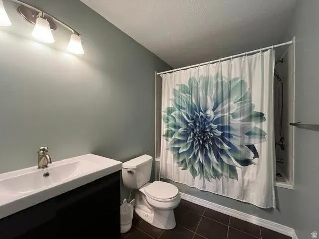 Wall-mounted vanity with integrated sink, modern toilet, and dark tile flooring
