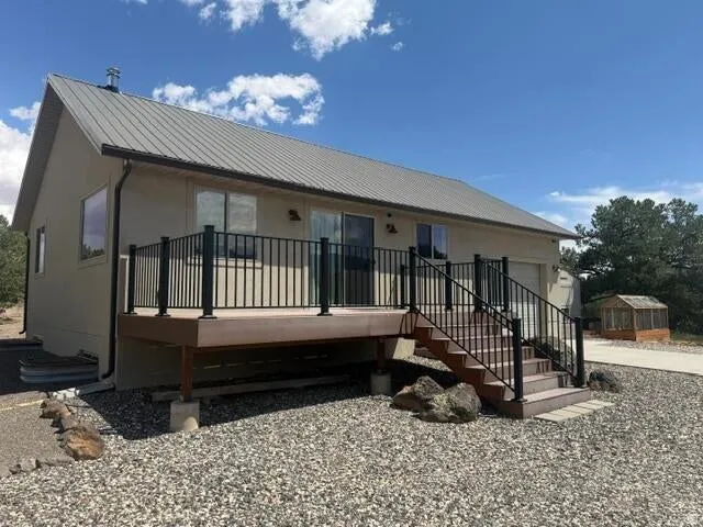 Exterior featuring a pitched metal roof, stucco siding, and a spacious deck with dark railing