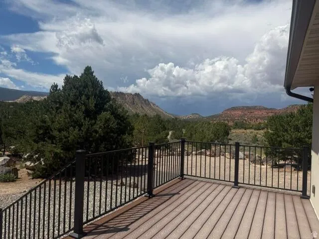 Expansive outdoor deck with composite decking and black metal railings, overlooking natural desert landscaping and distant mountains