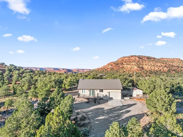 Contemporary single-story residence with a metal roof, attached garage, and a gravel driveway