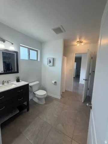 Dark wood vanity with a white countertop and rectangular undermount sink, complemented by a large mirror with integrated lighting