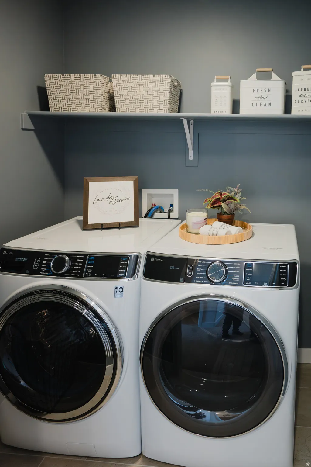 Dedicated laundry area with a white front-load washer and dryer set, complemented by a white wall-mounted shelf