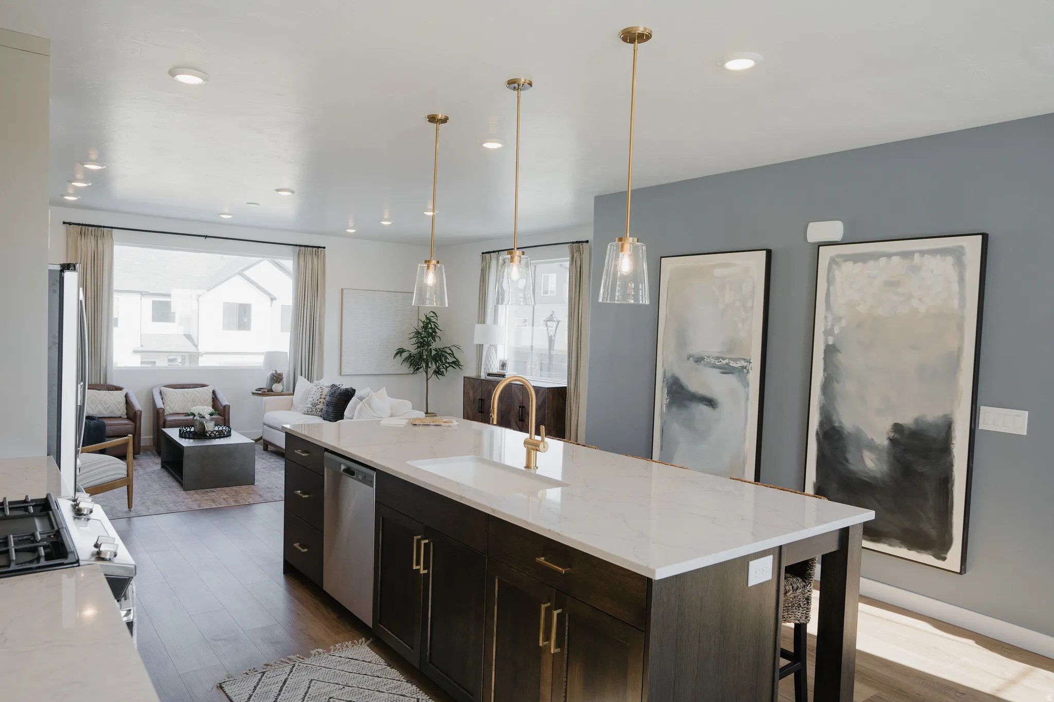 Spacious open-concept living area featuring an expansive kitchen island with a white countertop and brass-finish pendant lighting