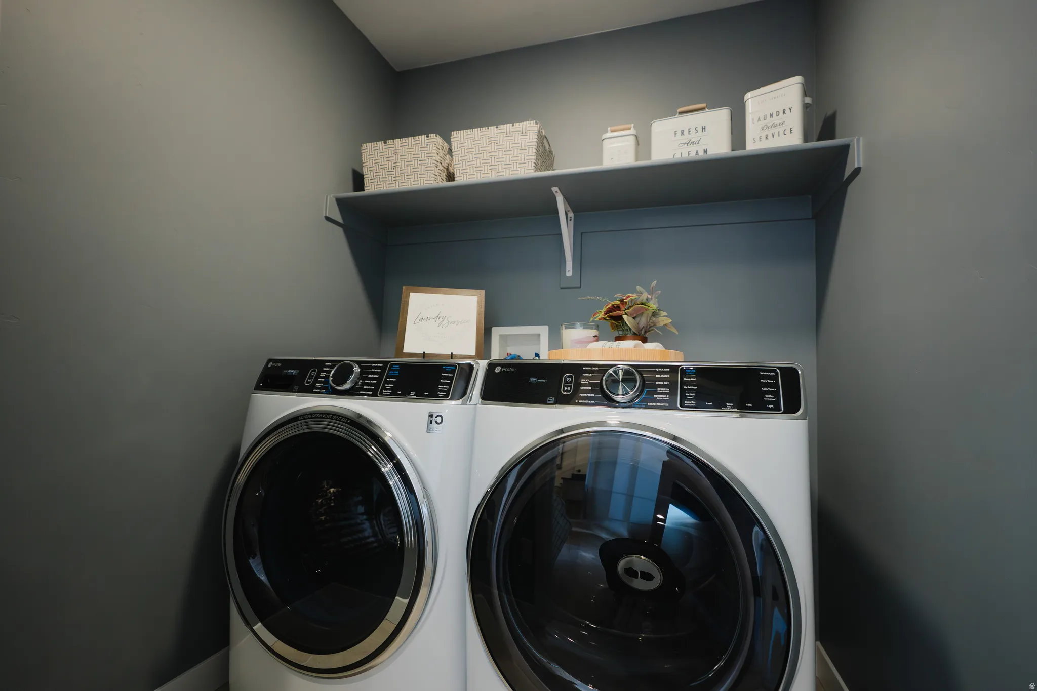 Dedicated laundry area featuring a built-in shelf for organized storage