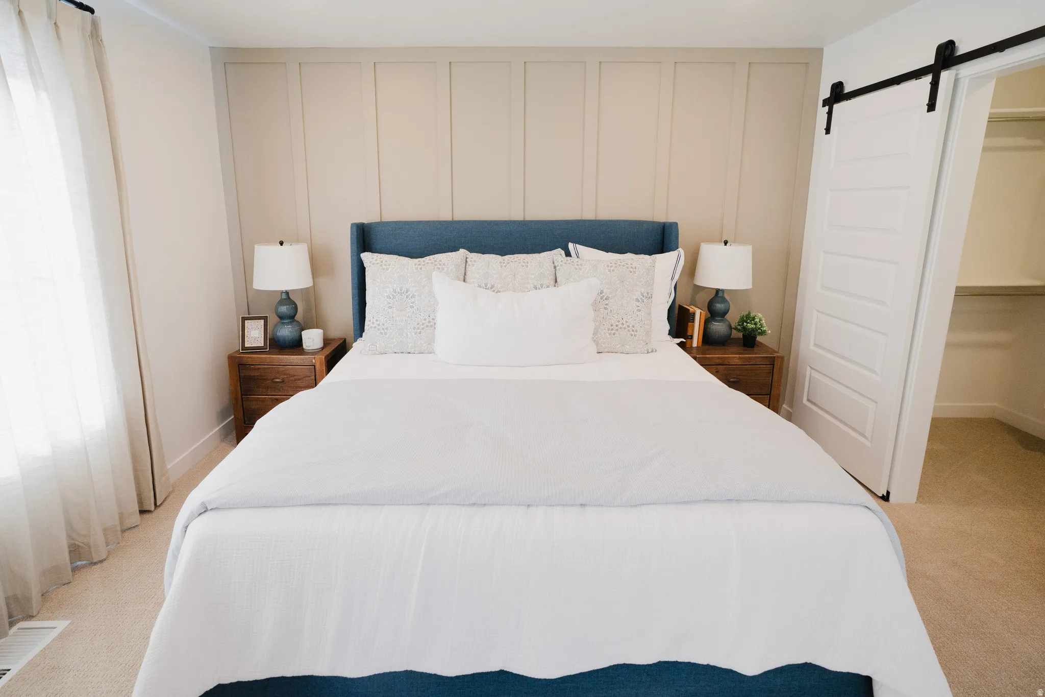 Board and batten accent wall, barn door entry, plush carpet flooring, recessed lighting, and a window with sheer drapes