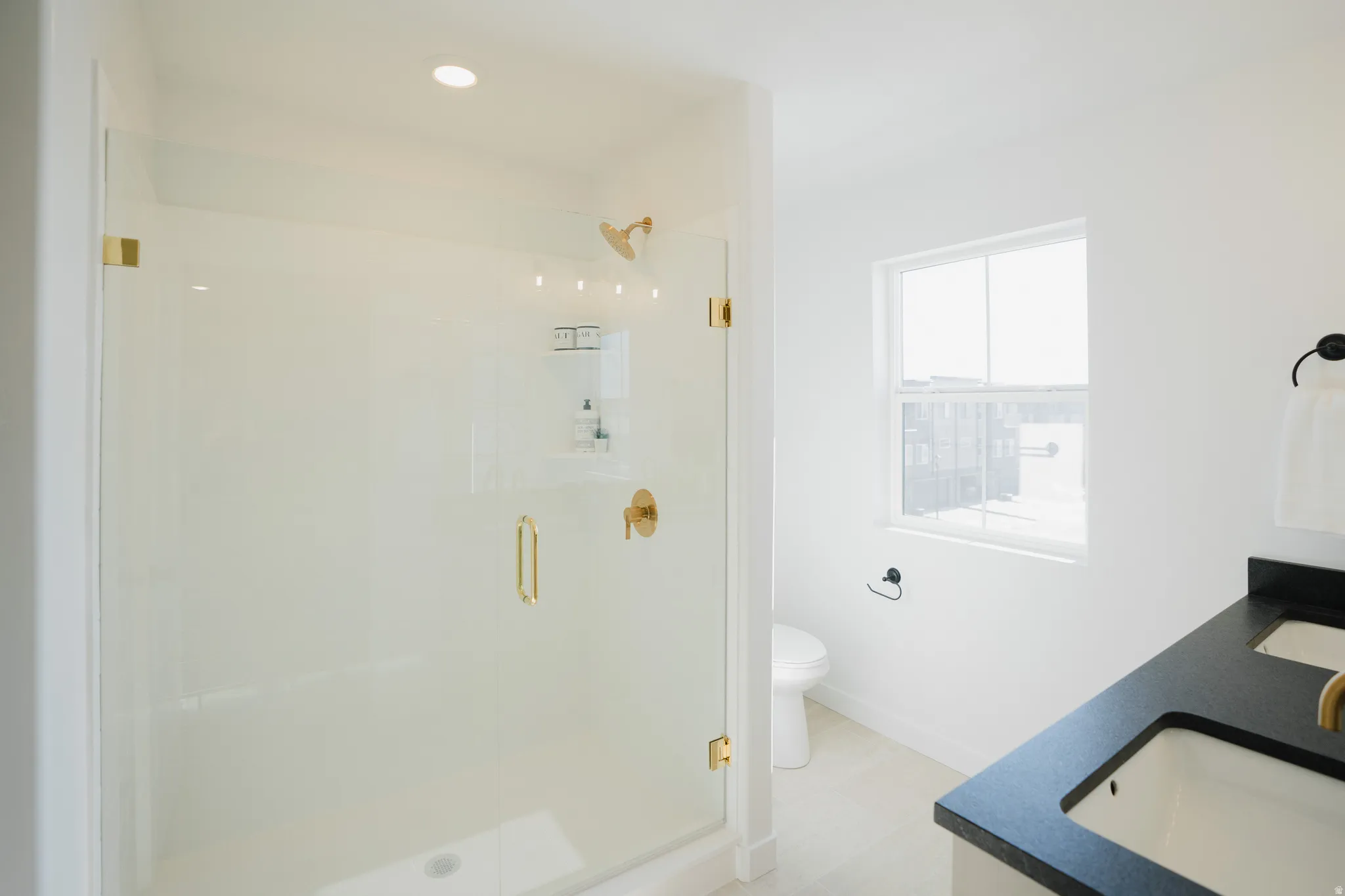 Glass-enclosed shower with gold-tone fixtures and recessed lighting
