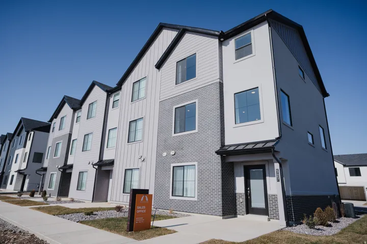 Contemporary multi-story facade featuring light gray siding, dark gray brick accents, and black trim