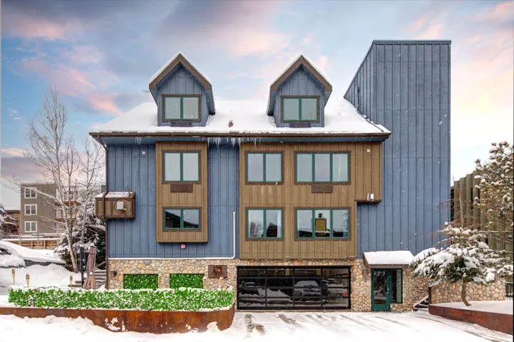 Modern exterior with varied siding, including blue vertical panels and warm wood-toned accents