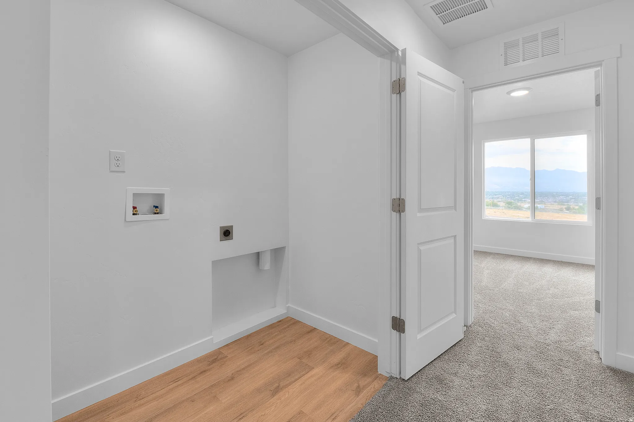 Dedicated laundry area featuring wood-finish flooring, washer hookups, and dryer vent