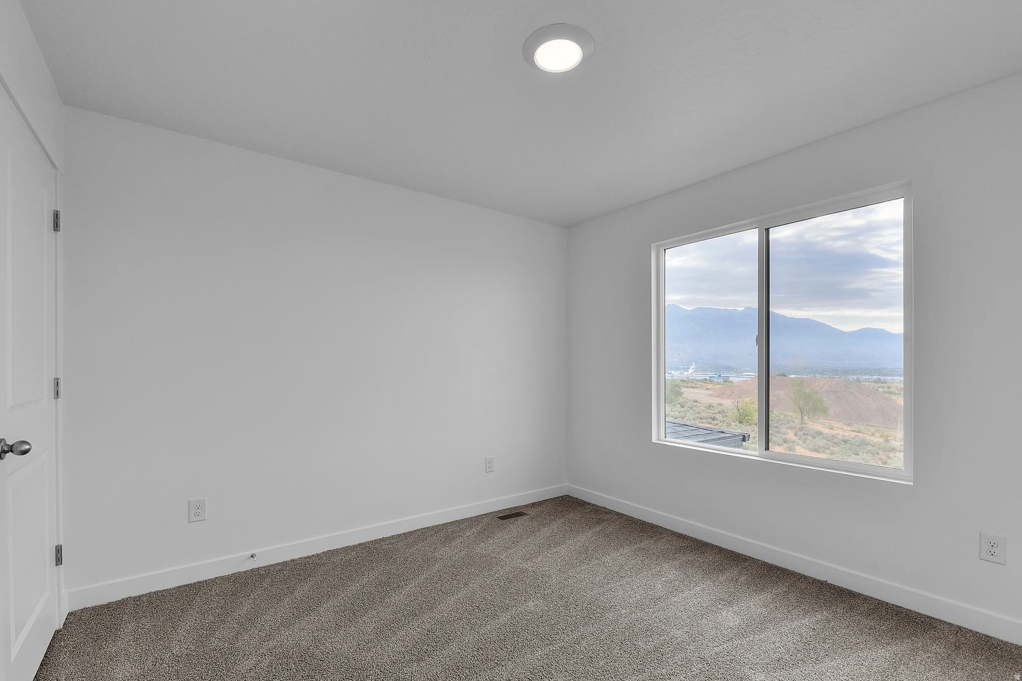 Room featuring a large window, neutral carpeting, white walls, and a recessed ceiling light