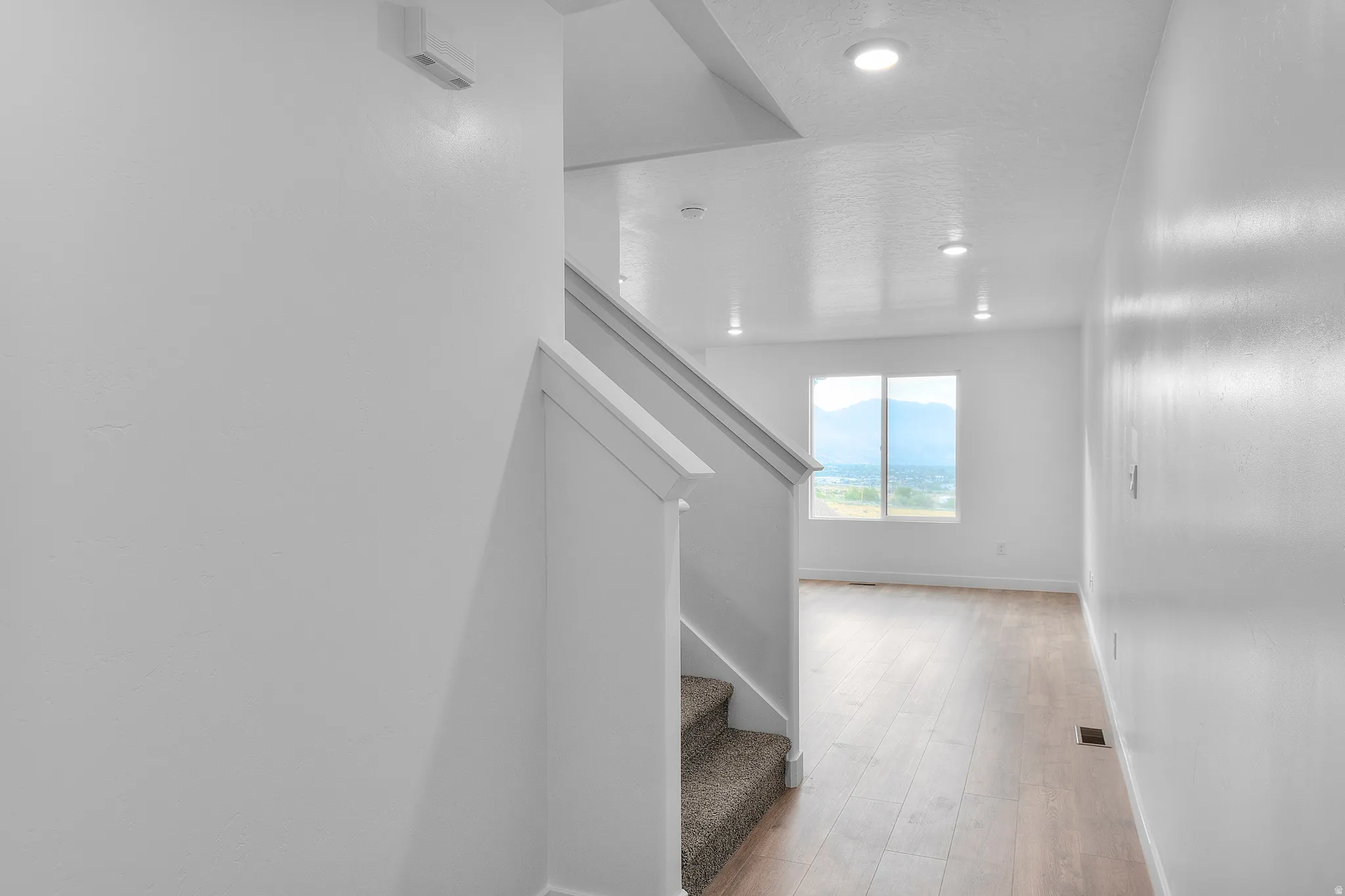 Open-concept hallway featuring wood-finish flooring, recessed lighting, and a window with mountain scenery