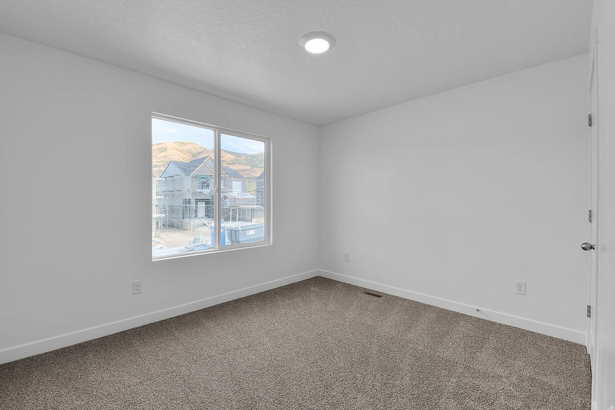 Neutral paint scheme bedroom featuring a large window, recessed ceiling light, and carpet flooring