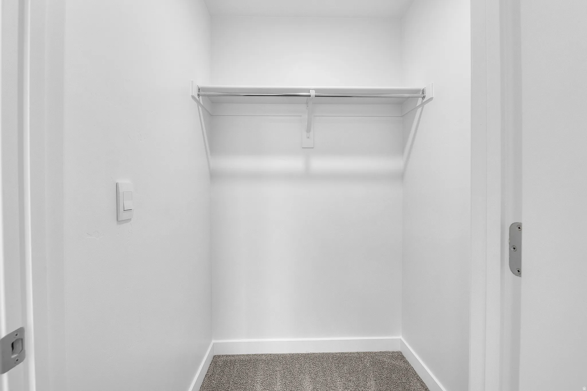 Recessed closet with a wire hanging rod, carpeted flooring, and white baseboards