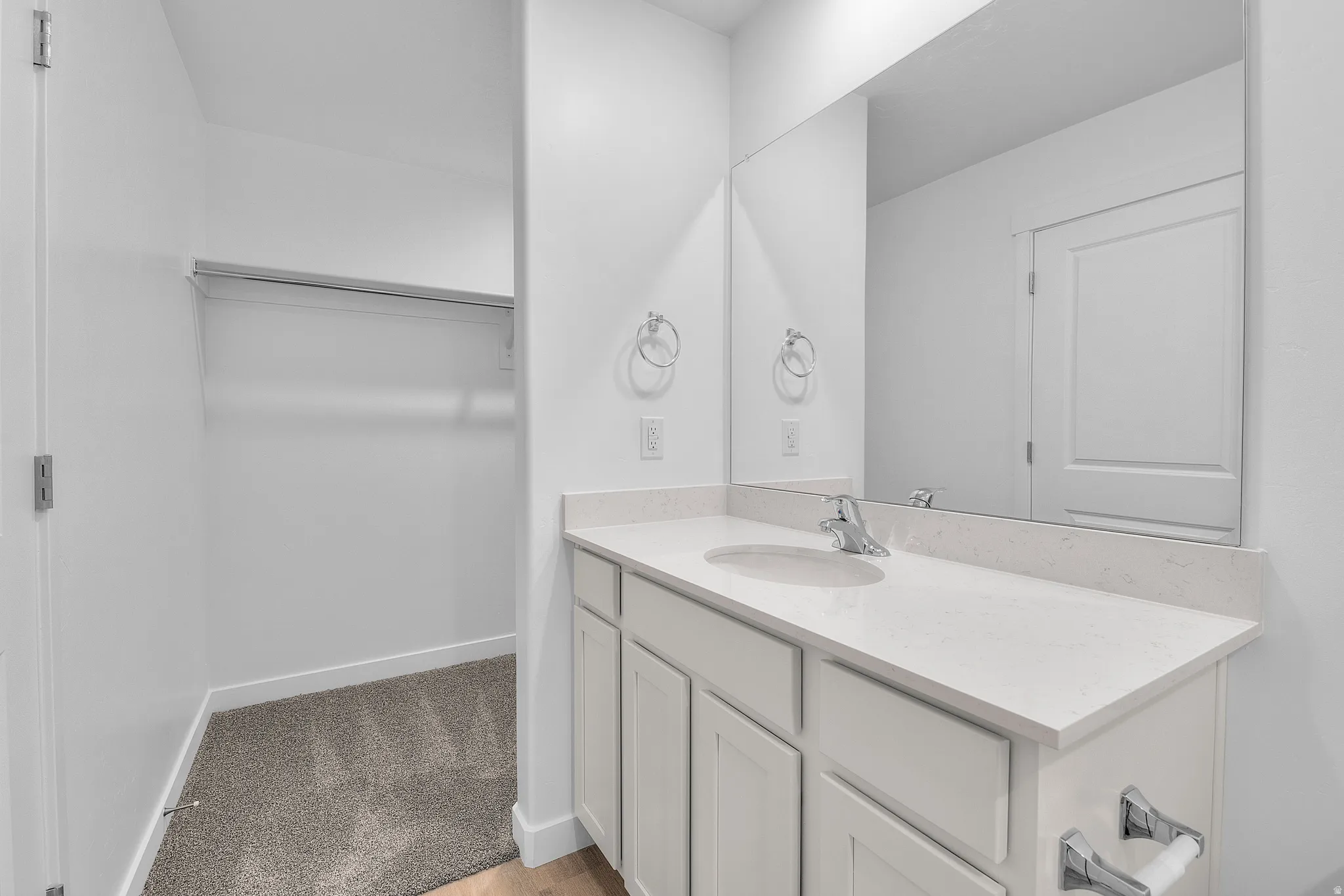 Bathroom vanity featuring a light-toned countertop, undermount sink, and chrome fixtures