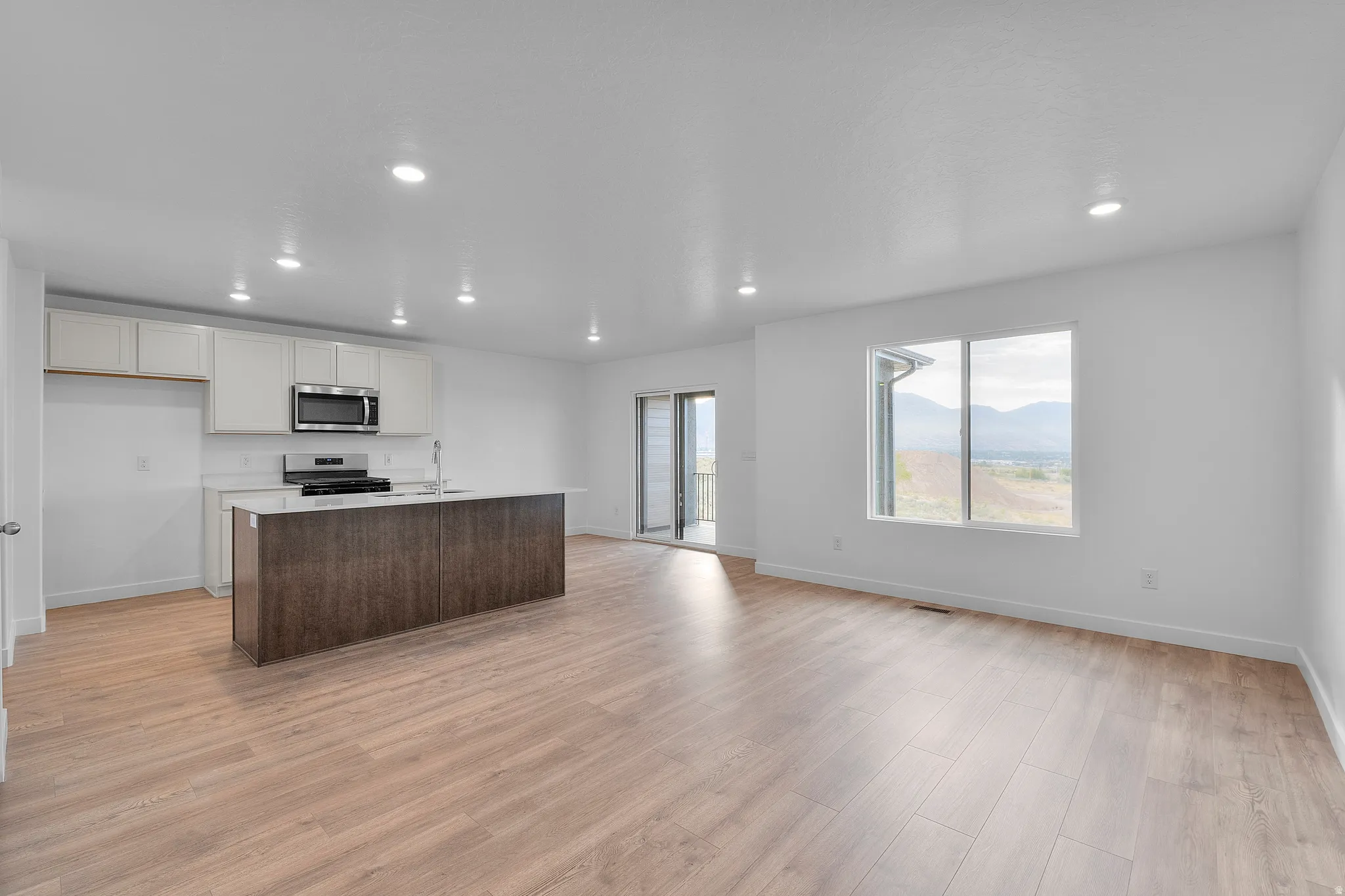 Open-concept living space featuring wood-finish flooring, recessed lighting, and white walls