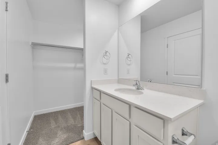 Bathroom vanity featuring a light-toned countertop, undermount sink, and chrome fixtures