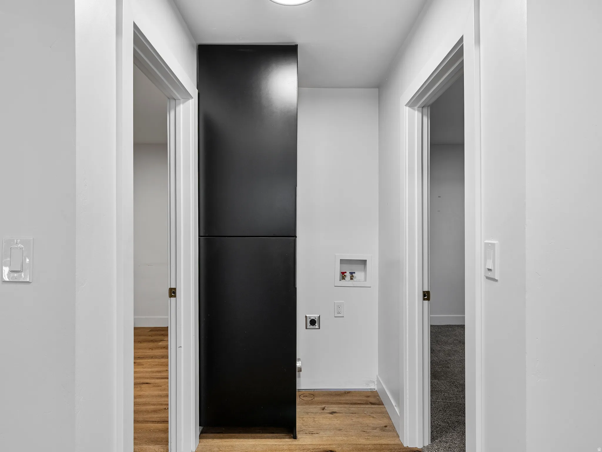Corridor with wood-finish flooring, white walls, and a recessed ceiling light