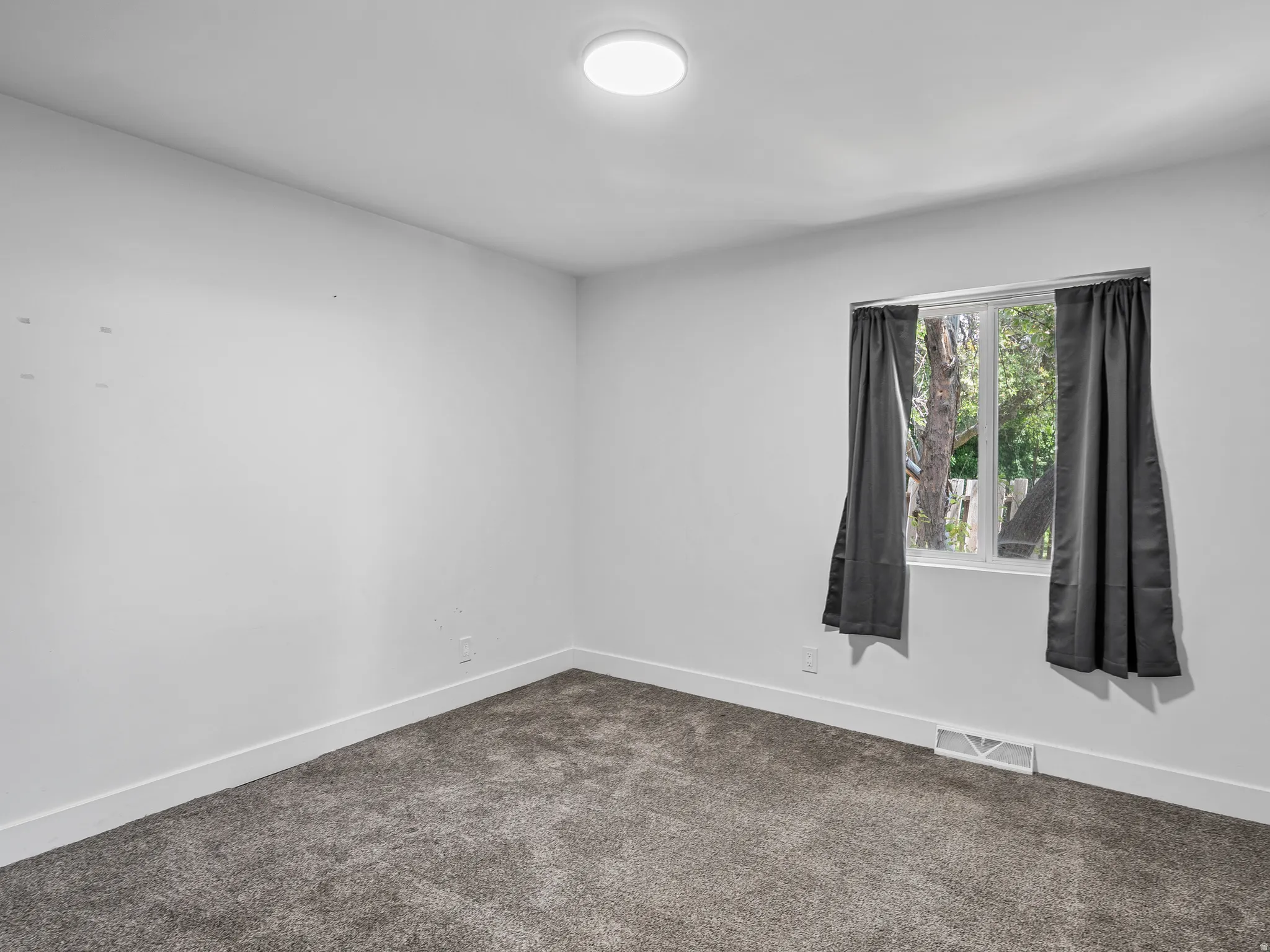 White interior walls with a single window featuring a tree-lined backdrop