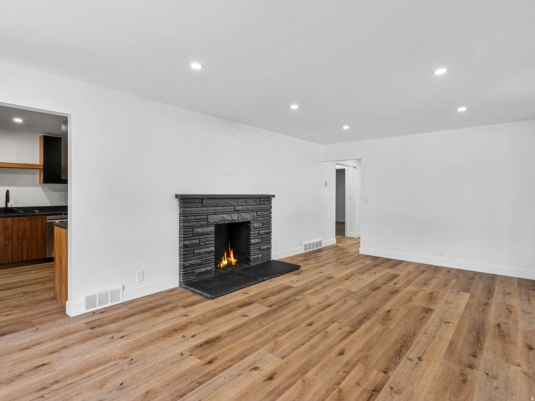 Living space featuring a stacked stone fireplace with a dark stone hearth