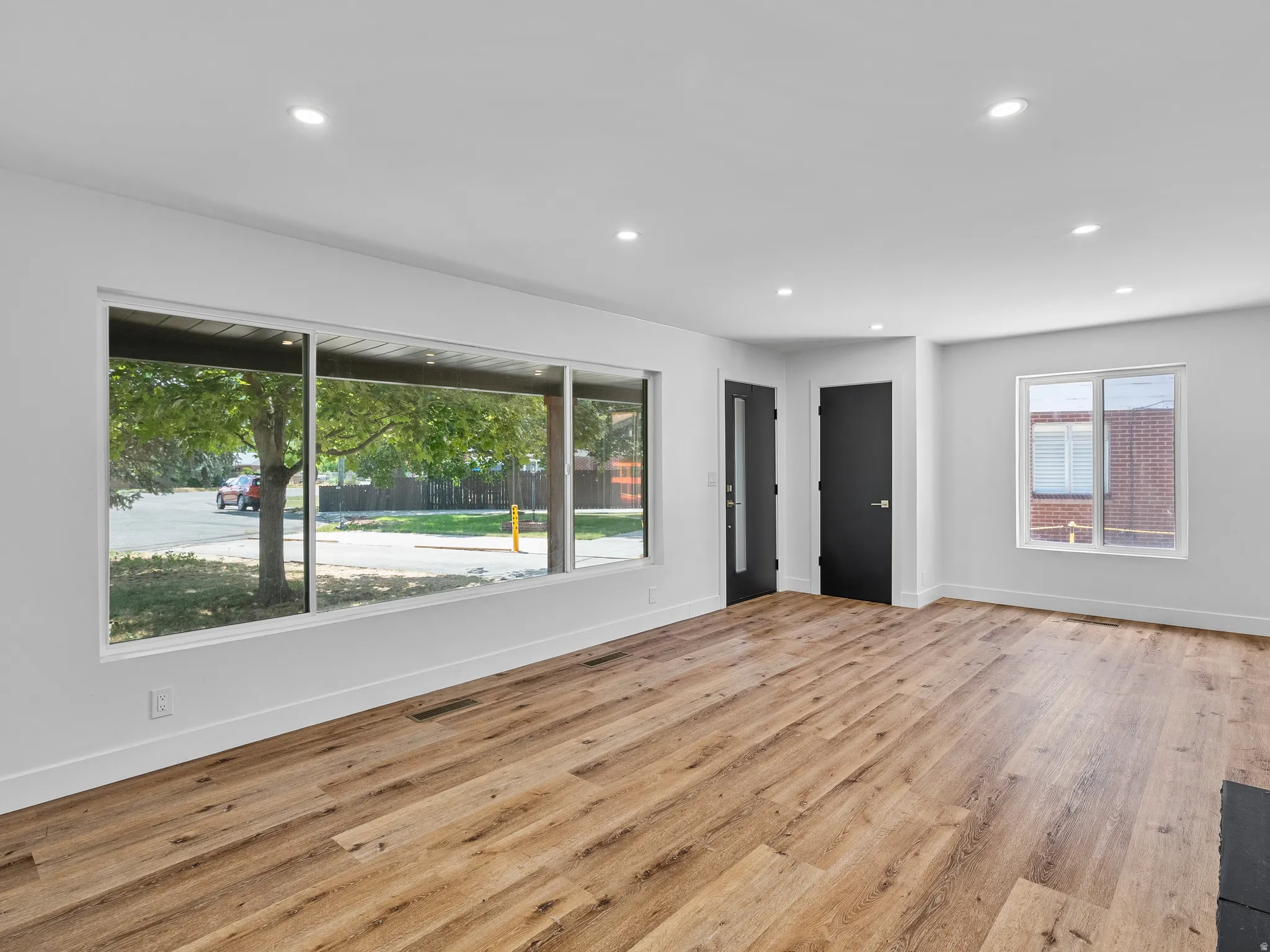 Spacious room featuring wood-finish flooring, recessed lighting, and white walls