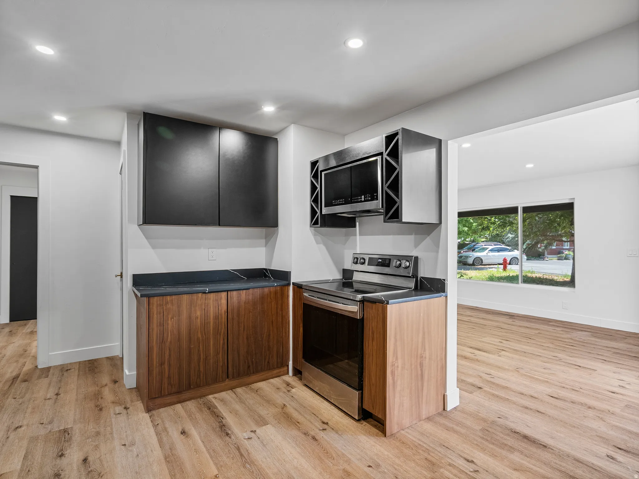 Kitchenette featuring a stainless steel range and microwave, dark wood-finish base cabinetry, black upper cabinetry, and dark countertops