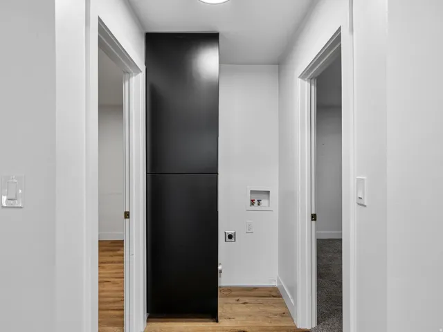 Corridor with wood-finish flooring, white walls, and a recessed ceiling light