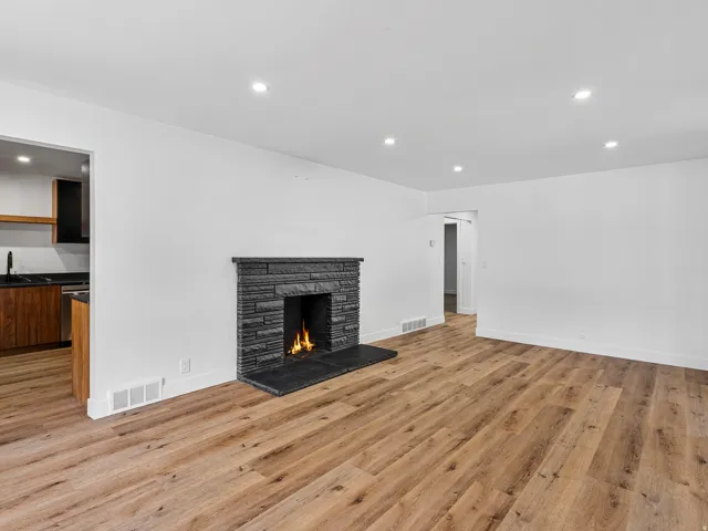 Living space featuring a stacked stone fireplace with a dark stone hearth