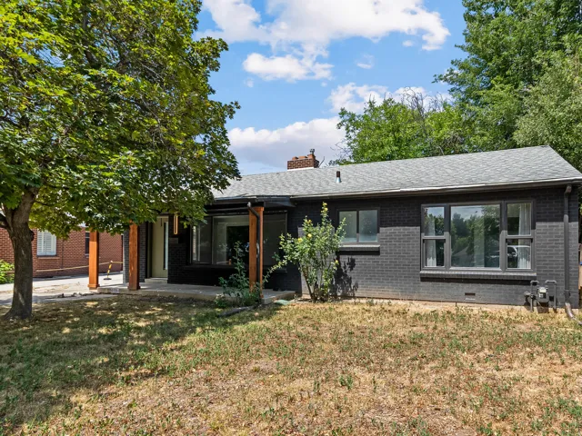 Single-story residence featuring a dark brick exterior, a grey shingle roof, and multiple large windows