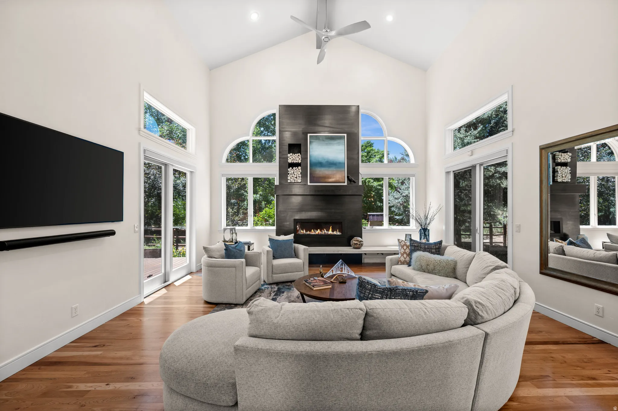 Spacious living area featuring a vaulted ceiling, floor-to-ceiling fireplace with an integrated linear fire feature, and multiple arched windows