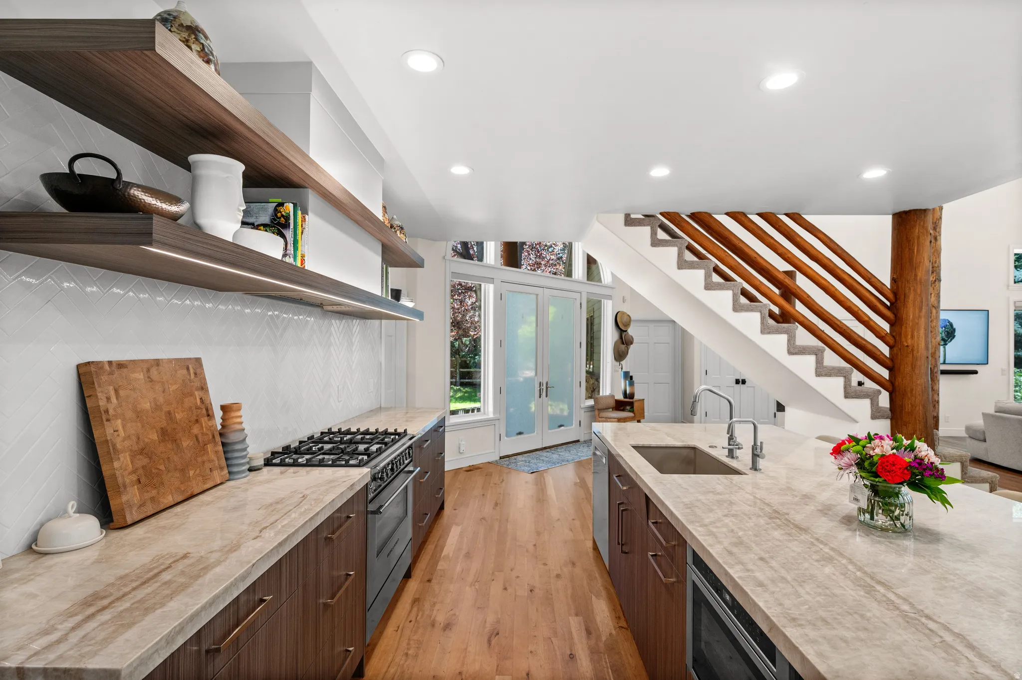 Gourmet kitchen featuring a built-in gas range, integrated double oven, and a large central island with an undermount sink