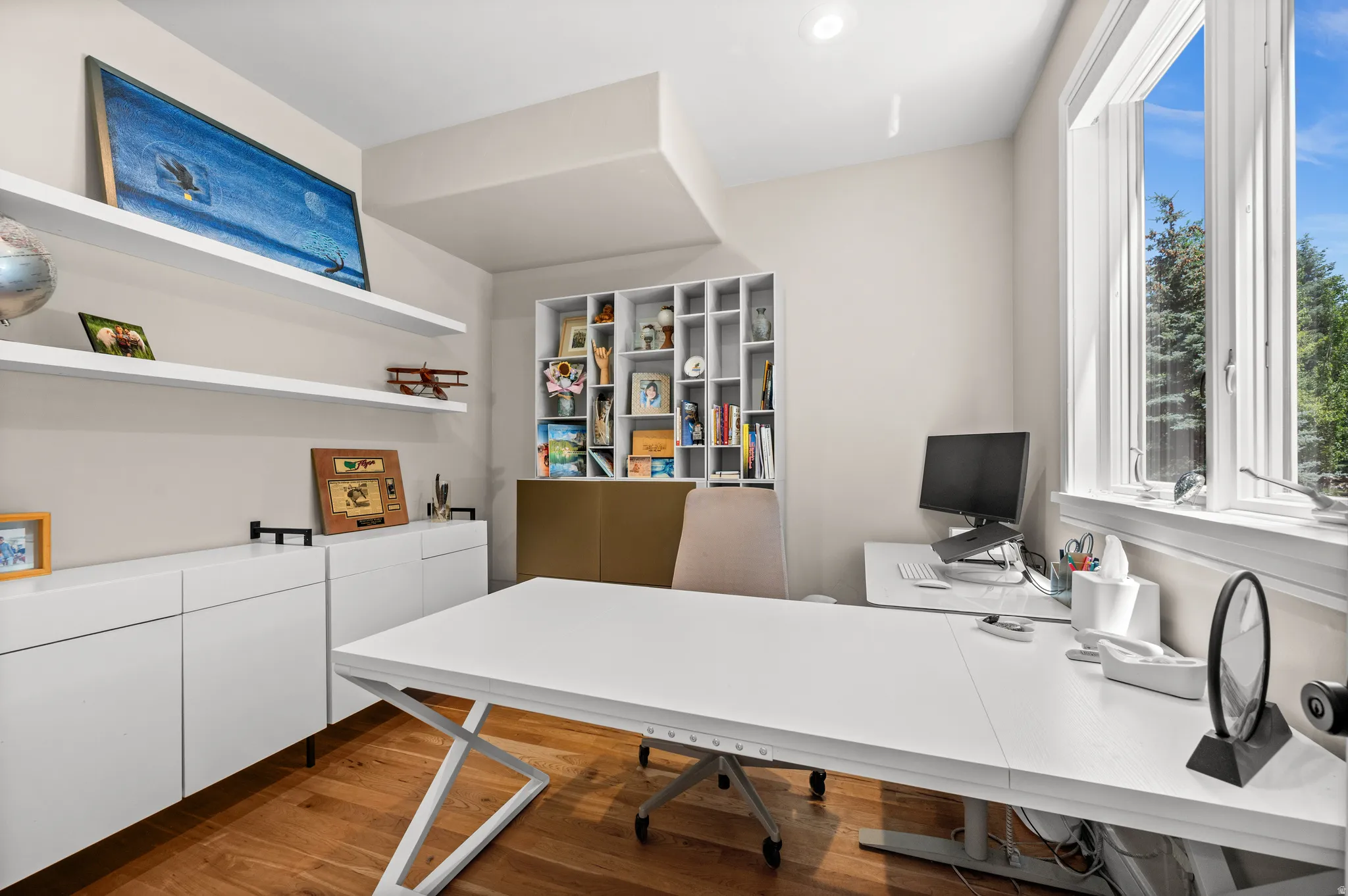 Room featuring hardwood flooring, a large window, recessed lighting, built-in shelving, and floating wall shelves