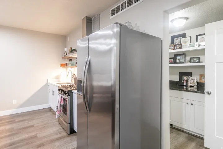 Kitchen featuring stainless steel appliances, wood-finish flooring, white cabinetry, a built-in range, and a stainless steel range hood