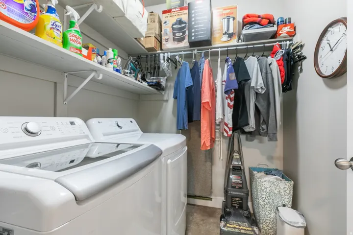 Dedicated laundry area with white shelving, a clothing rod, and neutral wall paint