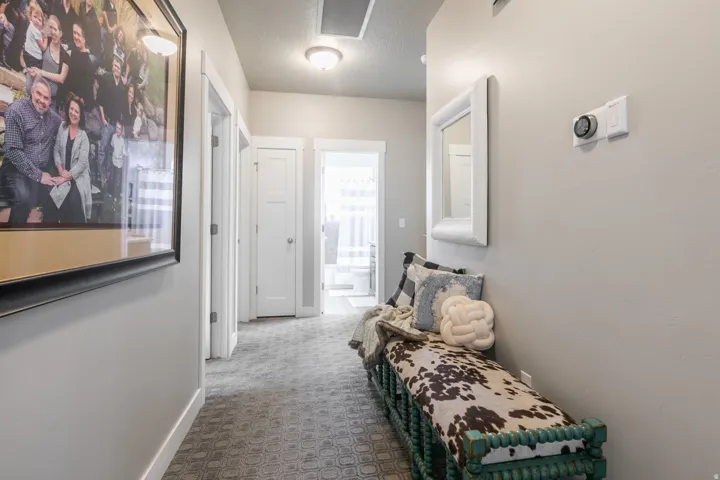 Hallway featuring a patterned carpet, recessed lighting, and a digital thermostat