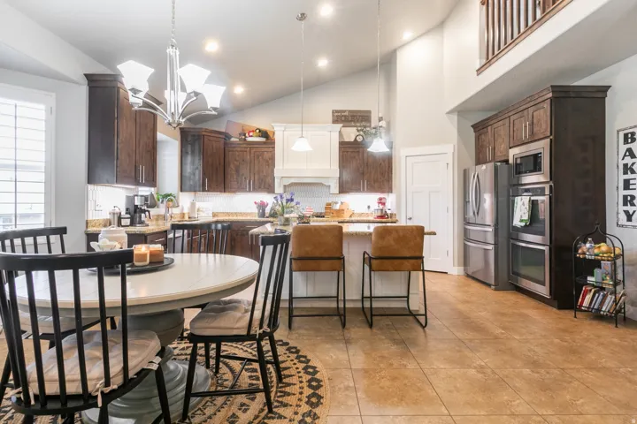 Kitchen featuring vaulted ceilings, wood-finish cabinetry, stainless steel appliances, and tile flooring