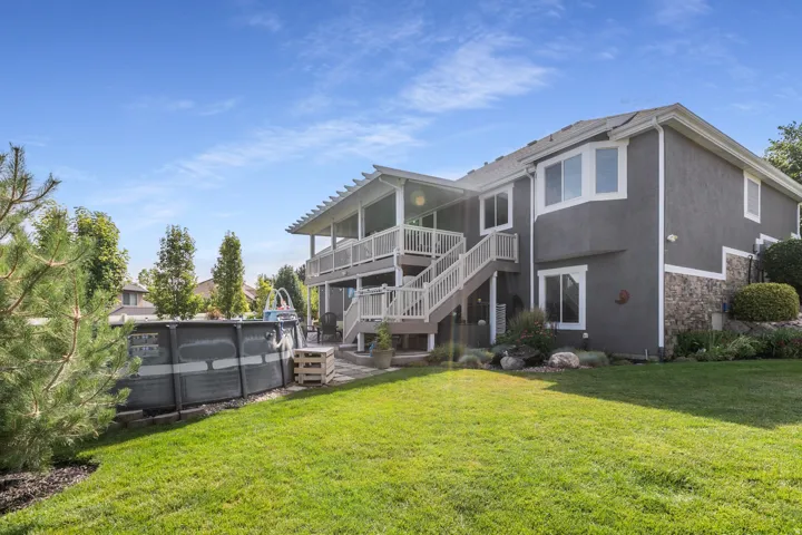 Expansive green lawn with a two-story stucco and stone-clad exterior