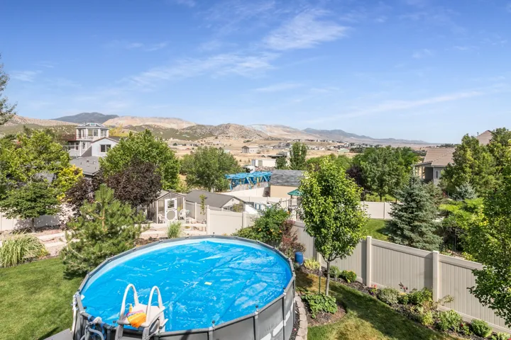 Expansive backyard featuring an above-ground pool, a manicured lawn, and mature trees