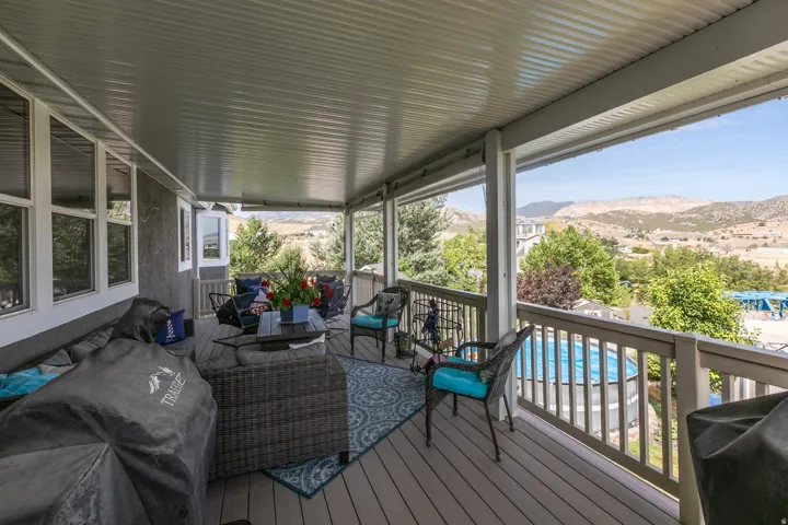 Covered outdoor deck featuring composite decking, white railing, and a slatted ceiling