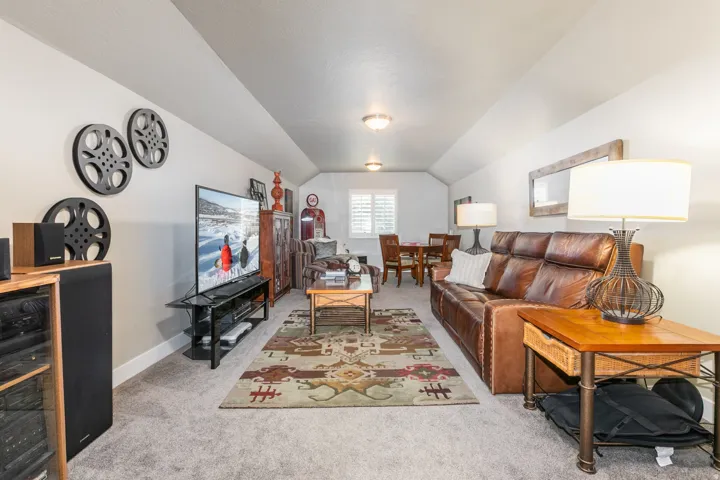 Spacious bonus room featuring vaulted ceilings, recessed lighting, and a large area rug complementing the neutral wall tones