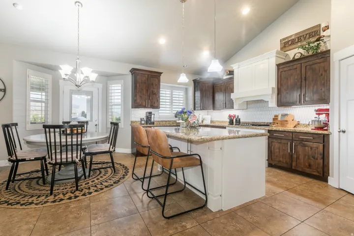 Kitchen featuring a large central island with bar seating, granite countertops, and a white beadboard base