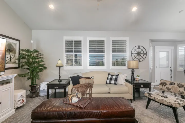Living area featuring three windows with plantation shutters, recessed lighting, and a neutral wall color