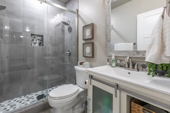Bathroom featuring a glass-enclosed shower with gray subway tile walls and a hexagonal pebble-tile floor