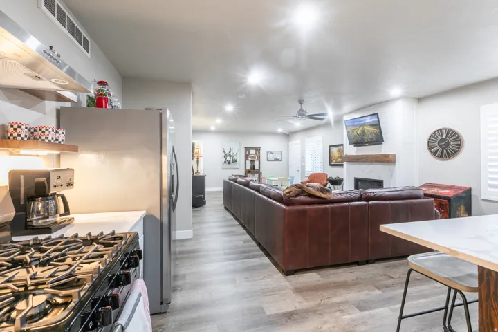 Open-concept living space featuring wood-finish flooring, recessed lighting, and a white brick fireplace with a wood mantel