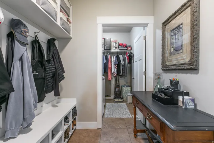 Integrated built-in mudroom storage featuring coat hooks, overhead shelving, and a bench with cubbies